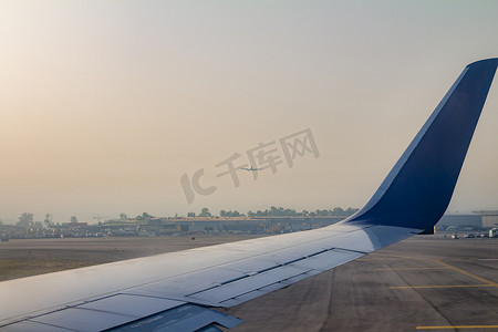 飞机机翼摄影照片_日出时本古里安机场跑道上的飞机机翼