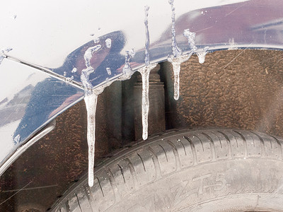 轮胎上方的汽车上挂着结冰的水冰柱