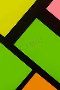 黑纸上的绿色、黄色、橙色和玫瑰色彩色办公室贴纸。 