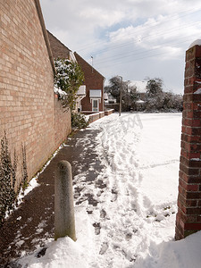 房屋后的人行道穿过英国庄园下雪的冬日