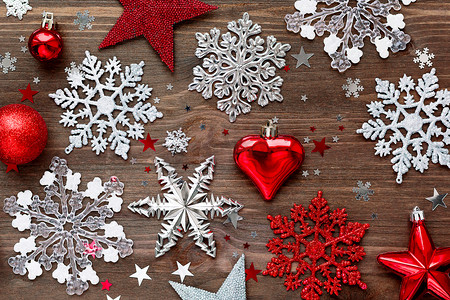 圣诞节和新年背景与圣诞装饰-球、星星、银色闪闪发光的雪花、心和木桌上的五彩纸屑。