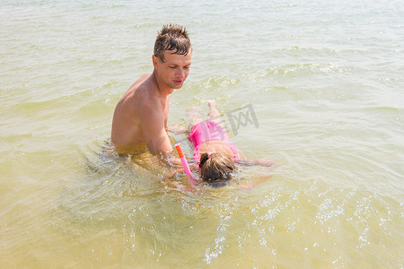 爸爸教他的女儿在水下戴着面具游泳
