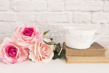 礼品卡模板摄影照片_白桌上的一束玫瑰，一大杯旧书上的咖啡，浪漫的花卉框架背景，花卉风格的墙壁模型，玫瑰花模型，情人节母亲节贺卡，礼品卡
