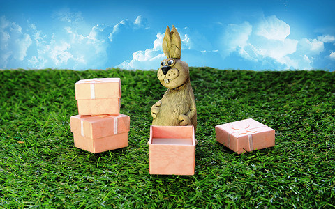 礼盒绿色摄影照片_带粉色礼盒的棕色复活节兔子