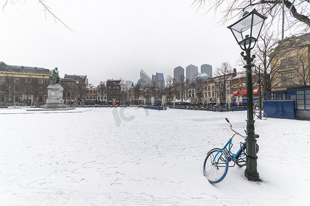 Plein（荷兰语）中央被雪覆盖的灯柱锁着自行车，在荷兰海牙的日落和温暖的天气里，通常挤满了吃饭和喝酒的人