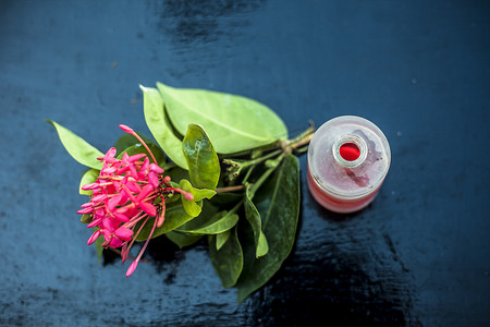 五角星标题栏摄影照片_木质表面红色五角花或埃及星花或茉莉花的特写，其提取的精油在透明瓶中。