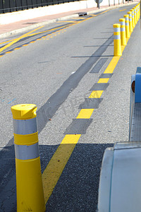 黄色条纹摄影照片_沿路的黄色条纹杆划分交通方向，道路安全的概念