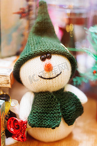 冬天手工雪人摄影照片_圣诞节和新年背景与手工制作的玩具-带红铃的针织雪人。