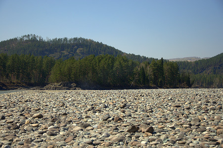 绿色卡通横幅摄影照片_卡吞河的大河岸上铺满了圆石，背景是高山。