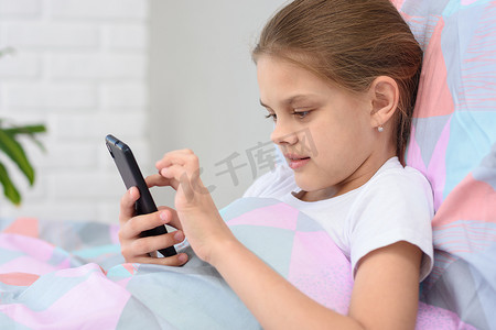 女孩躺在床上玩手机