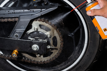 用油喷雾清洁和上油摩托车链条和齿轮。