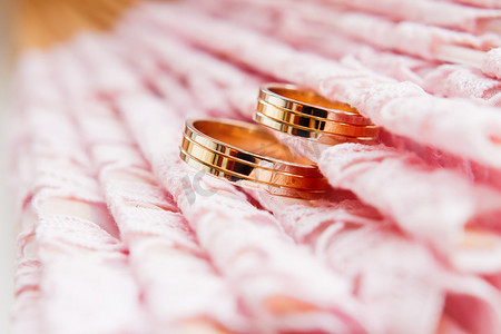 花边粉红色织物上的金色结婚戒指。