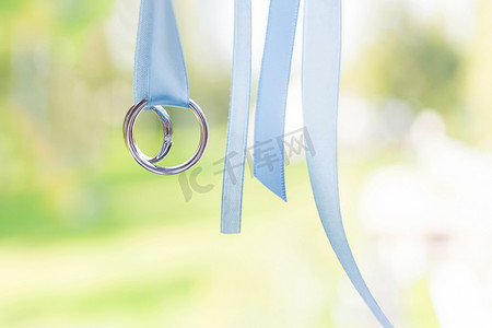 金色钻石摄影照片_一对金色结婚戒指，浅蓝色丝带上镶有钻石。