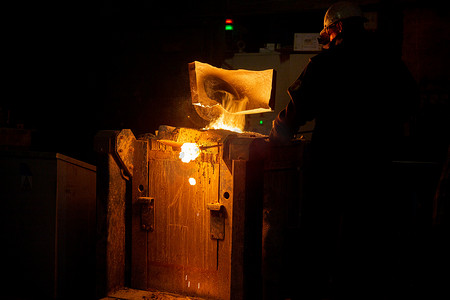 工人用排气罩从冶金炉中除渣并用蒸汽熔化金属