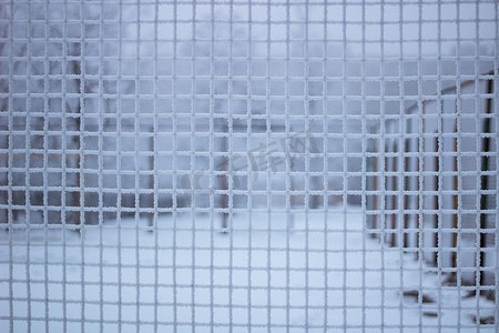冬季在冷淡的金属网后面下雪的运动场