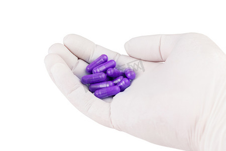 胶囊紫色摄影照片_手持质子紫色有机药物胶囊的医用手套，白色背景特写