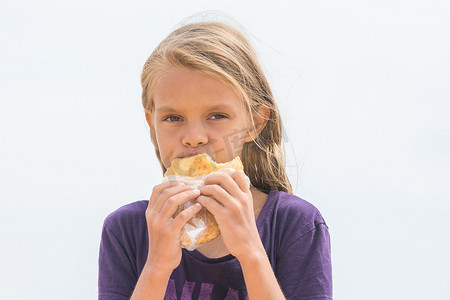 一个有胃口的饥饿女孩嚼着美味的蛋糕，看着画框