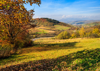 秋天风景与草地和山的村庄
