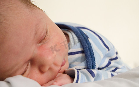 两周大的新生男婴睡在白床单上
