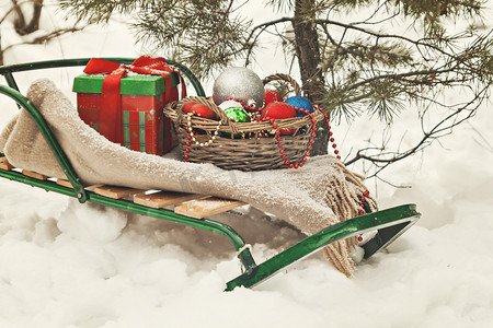雪橇、毯子、带玩具的篮子和雪地里的礼盒