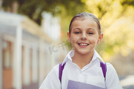 女学生站立摄影照片_站立在校园的愉快的女小学生