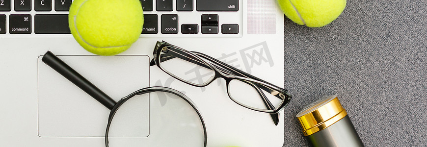 笔记本电脑、运动器材、网球、羽毛球、体育管理灰色桌子上的眼镜的顶视图。经营理念。