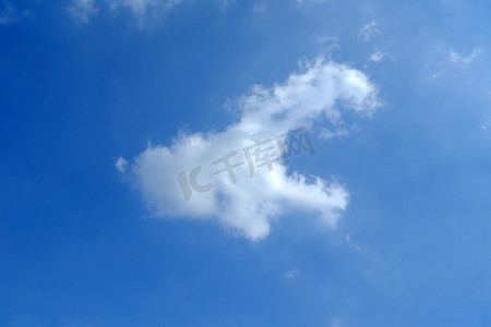 周而复始摄影照片_与云彩的蓝天在狗形状背景中。