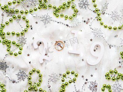 2019新年背景摄影照片_圣诞节和新年背景与数字 2019、绿色装饰、结婚戒指和灯泡。