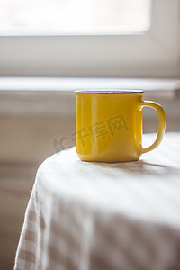 咖啡茶摄影照片_阳光明媚的桌子上放着一杯黄色的咖啡茶