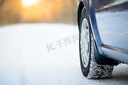 汽车性能摄影照片_冬季汽车轮胎在雪路上的特写图像。