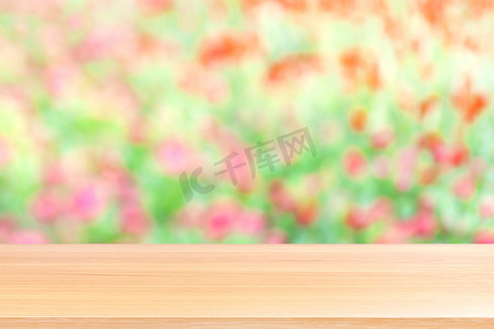 木板在模糊的花粉红色和绿色柔和的背景上，空木桌地板在模糊的花粉红色柔和的花园自然背景上，木桌板是空的，用于模拟展示产品