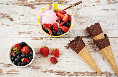 粉色冰淇淋配浆果-黄色碗中的草莓和蓝莓。