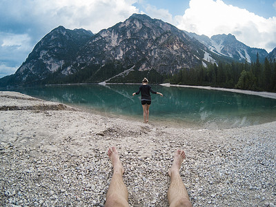 男人的腿和女人站在 Braies Lake Lago 的壮丽景色中，山脉倒映在意大利白云岩阿尔卑斯山的湖水中。