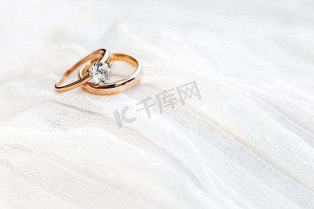 白色织物上镶有钻石的金色结婚戒指。