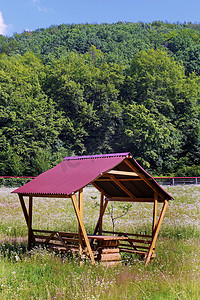在明亮的炎热夏日阳光下，带红色屋顶的木制凉亭