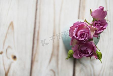 扁平文字框摄影照片_木制背景上有一束粉红色玫瑰的花瓶，上面放着你的文字。