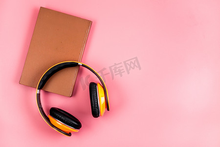 有声读物的概念，耳机放在粉红色的桌子上，从上面的复制空间