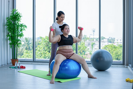 肥胖女性摄影照片_亚洲胖女人和教练在健身课上锻炼，教练建议肥胖女性进行减肥运动