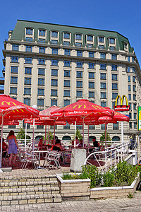 麦当劳咖啡馆在露台上，在城市一座高大的房子的背景下有雨伞
