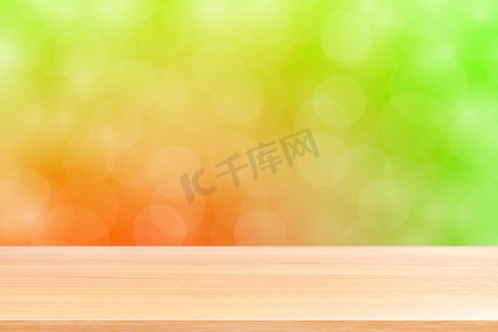 空木桌地板在模糊的散景柔和的红色绿色渐变背景上，木板空在绿色散景彩色光罩上，彩色散景灯渐变软，用于横幅广告产品