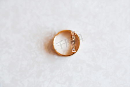 金色的结婚戒指与白色图案背景上的钻石。