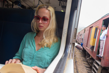 旅行记摄影照片_火车上靠窗的金发白种女人在看书。