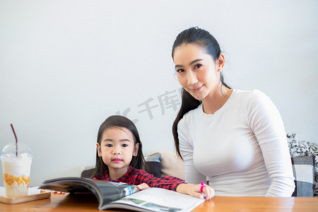 一位亚裔母亲正在教她的女儿在 t 期间读书