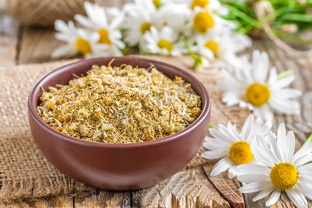 黄色菊花叶摄影照片_木质乡村背景中的干鲜洋甘菊花叶，替代药物