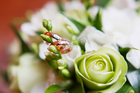 金色的花朵摄影照片_带有装饰品的金色结婚戒指位于花束中的花朵内。
