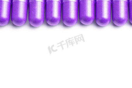 在白色背景上分离的一排质子紫色有机胶囊，特写有选择的焦点