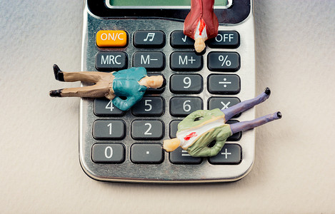 小图标金融摄影照片_带有键盘的计算器设备上的男士小雕像