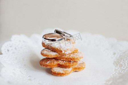 镶有钻石的金色结婚戒指躺在一堆甜饼干上。