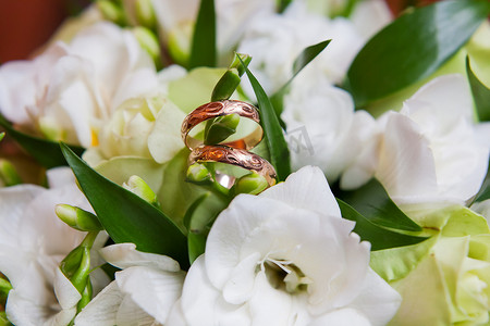 带有装饰品的金色结婚戒指位于花束中的花朵内。