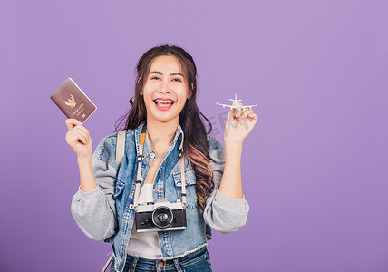 拿着飞机玩具、护照和古董相机的女人在暑假里兴奋地微笑